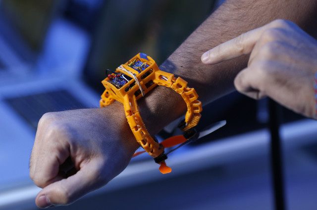 An attendee wears a prototype Nixie camera drone during the International CES Thursday, Jan. 8, 2015, in Las Vegas. The small drone, designed to be worn on the wrist, can be thrown into the air and automatically take a picture or video clip of the user. (AP Photo/John Locher)